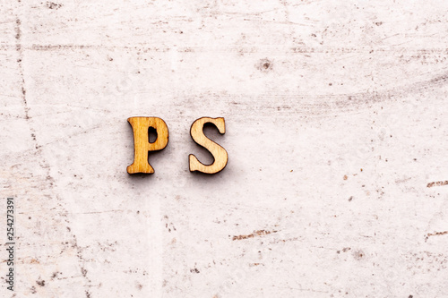 Inscription PS post scriptum abbreviation in wooden letters on a light background photo