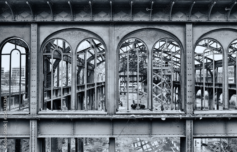 Fototapeta Facade and metallic structure of ancient factory partially demolished. Black and white photo.