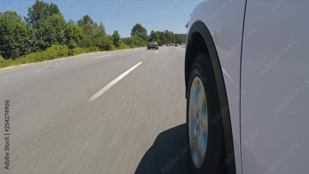 POV of car wheel on white car driving down highway