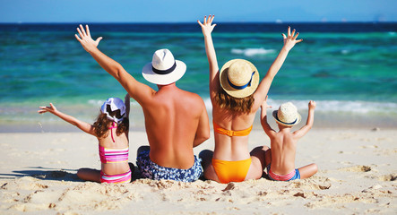 happy family father, mother and children backs on  beach at sea.