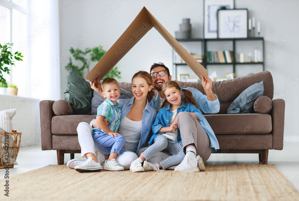 concept of housing and relocation. happy family mother father and kids with roof at home . concept of housing and relocation. happy family mother father and kids with roof at home .