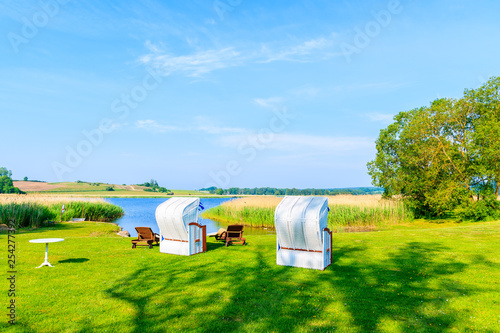 Wicker chairs in green area along lake shore in Seedorf village, Baltic Sea, Germany © pkazmierczak