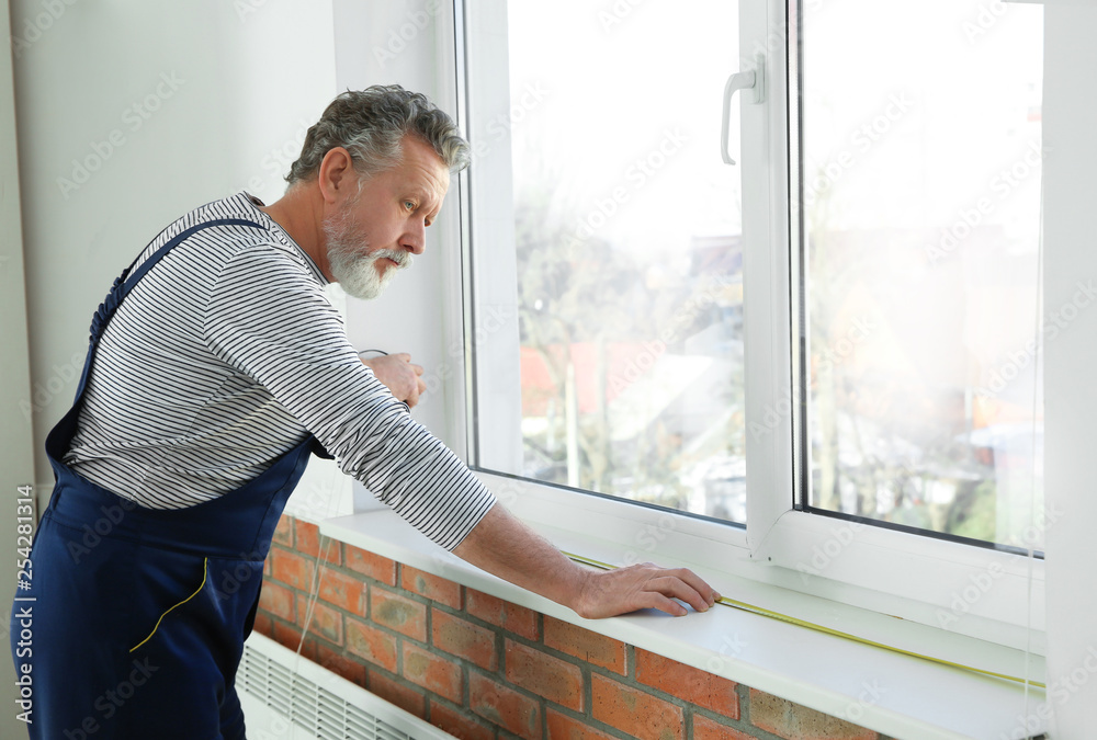 Fototapeta premium Service man measuring window for installation indoors