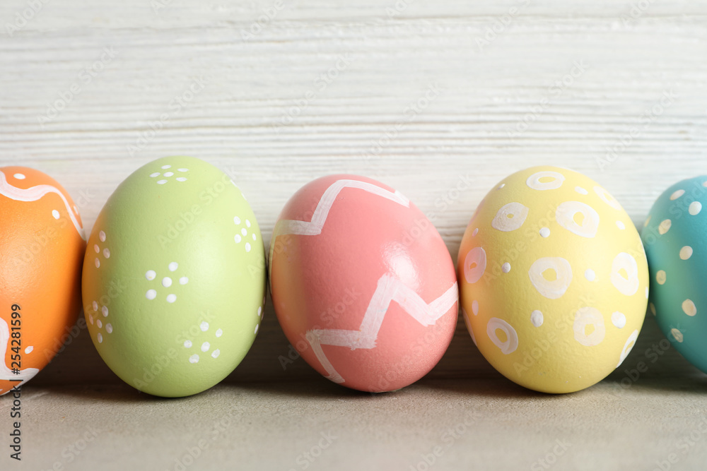 Colorful painted Easter eggs on table against wooden background, closeup