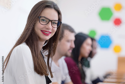 Group of students study in modern school computer lab classroom. Beautiful female student looking into camera.