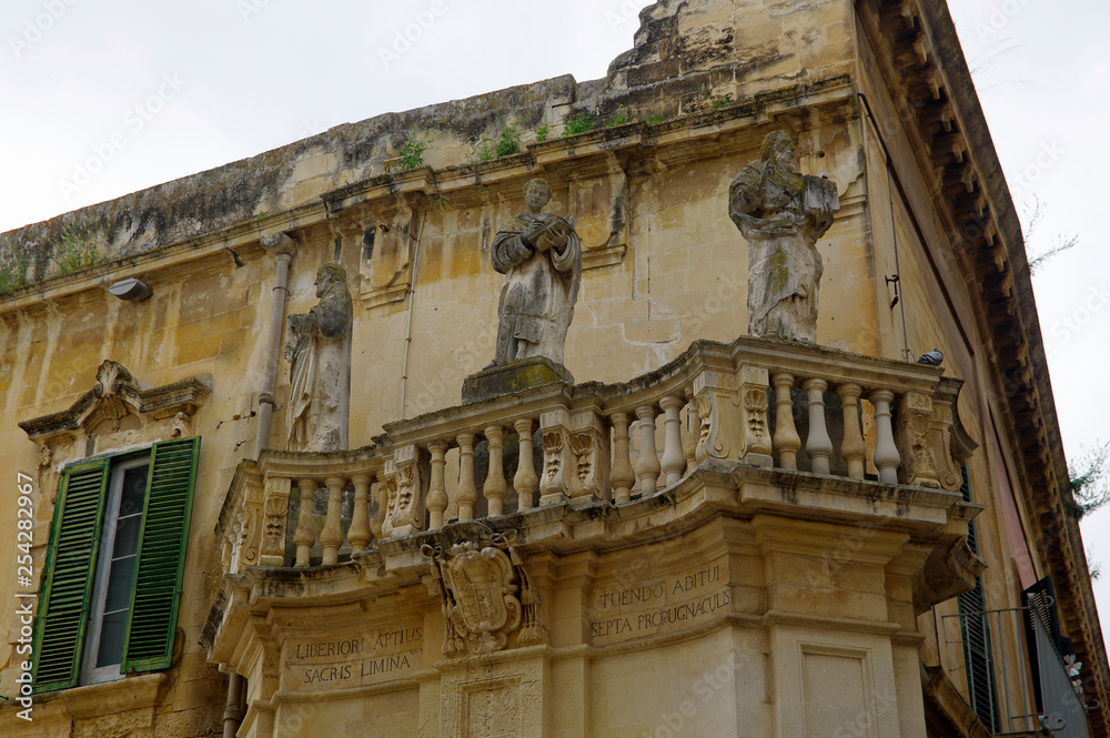 Charming balcony with baroque statues as example of typical architecture in Lecce in the Apulia region, Italy