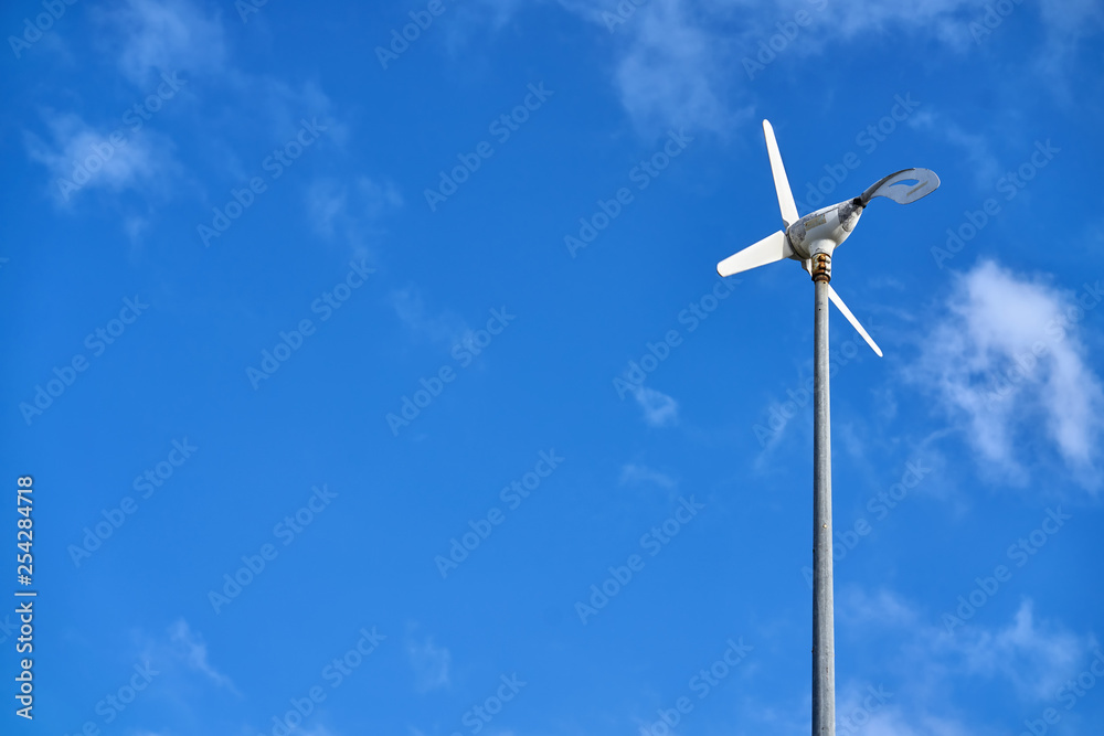 Sun is shining onto wind generator on blue sky background