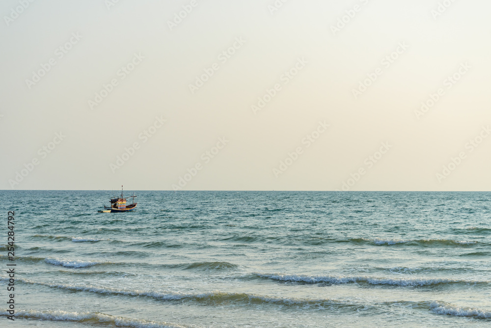 Single fishing boat float and drop anchor on the sea and background of sunset sky, view from a beach.