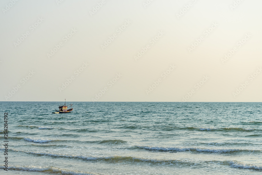 Fototapeta premium Single fishing boat float and drop anchor on the sea and background of sunset sky, view from a beach.