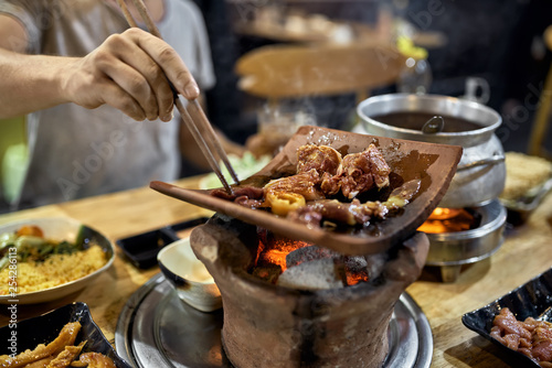 Visitor of traditional vietnamese restaurant cooking meat on hot pot