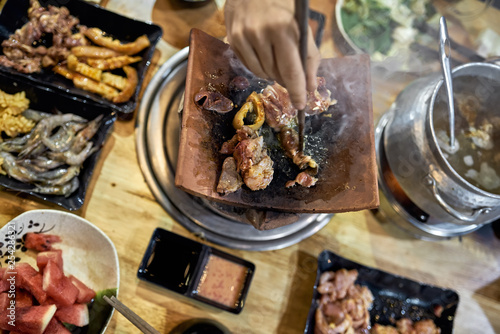 Visitor of traditional vietnamese restaurant cooking meat on hot pot