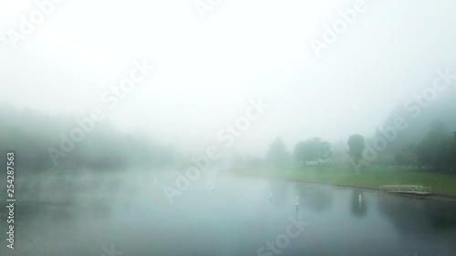 Drone hovering over early morning misty lake with islands in the background. photo