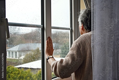 The old lady looks out of the window to the rain