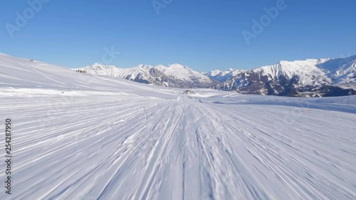 skiing first person point of view riding long white snowy track with clear blue sky