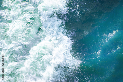 Fototapeta Naklejka Na Ścianę i Meble -  bright blue surface of ocean water with waves, spray and white foam, background, texture