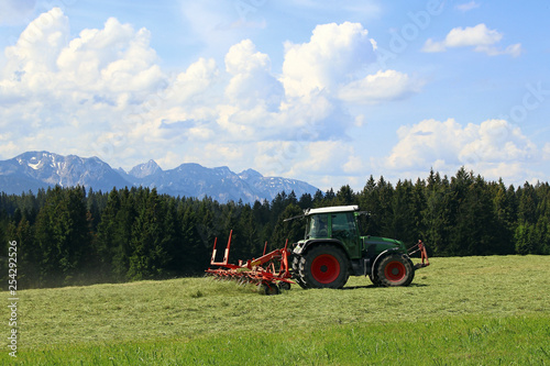 Im Sommer mäht ein Bauer mit seinem Traktor in Bayern Gras