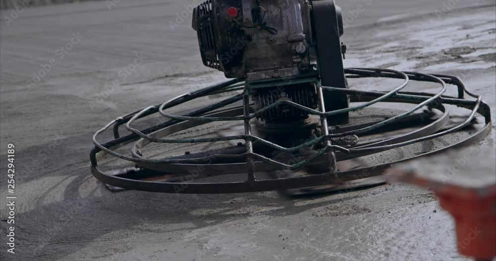 Slow motion close up of a concrete power trowel smoothing concrete at construction site view 2