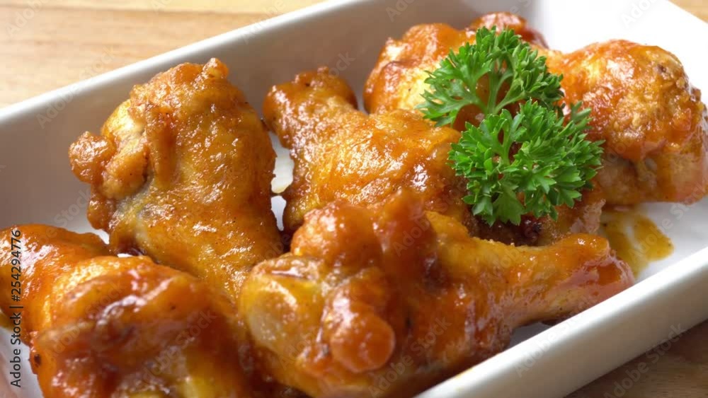 Slow pan of chicken drumsticks on a rectangular white plate Slow pan of chicken drumsticks on a rectangular white plate