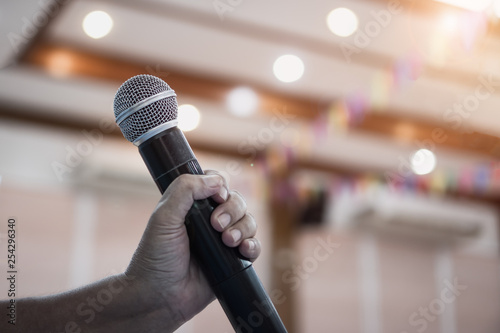 Speaker holding microphone for speak, presentation on stage in public conference seminar room. Business meeting and education in teaching classroom concept. Event light convention hall Background