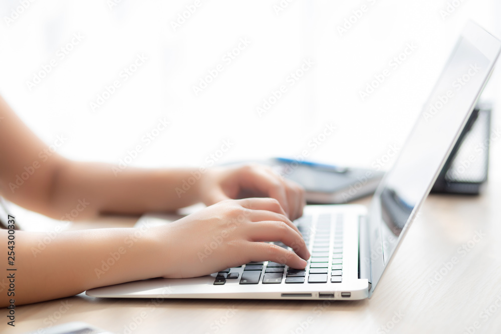 Closeup freelance asian woman working and typing on laptop computer at desk office with professional, girl using notebook checking email or social network, business and lifestyle concept. Closeup freelance asian woman working and typing on laptop computer at desk office with professional, girl using notebook checking email or social network, business and lifestyle concept.