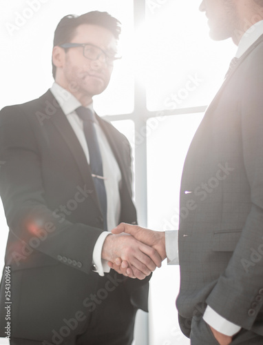handshake business partners on the background of the workplace