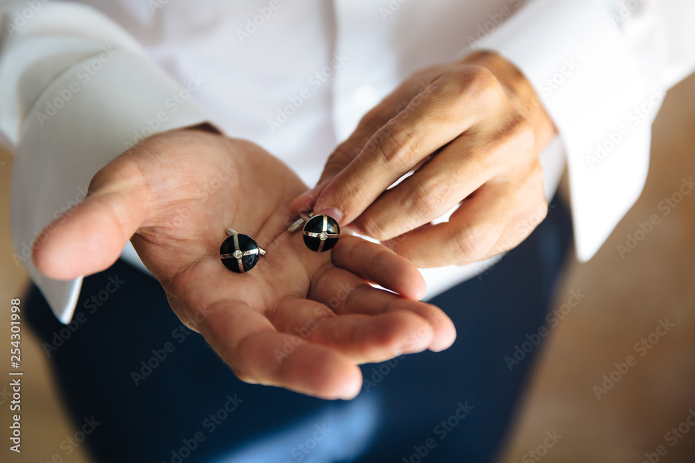 Closeup businessman hands with cufflinks. Man in a business suit, white shirt. Preparing the groom on the wedding day
