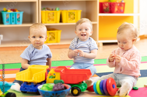 Nursery babies girl and boys playing together in playroom in kindergarten