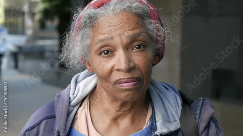 Elderly African American homeless woman looks directly into camera with sad eyes