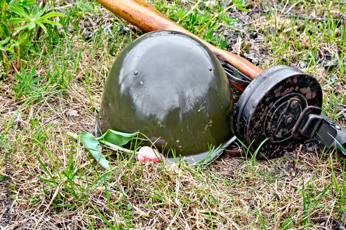 Helmet and submachine gun with tulip on grass