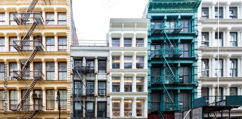 Exterior view of a block of colorful old historic buildings along Greene Street in the SoHo neighborhood in New York City with pattern of windows and fire escapes