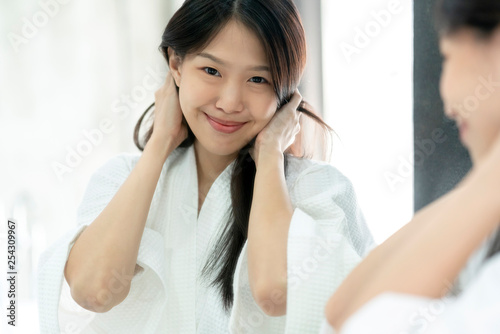 beautiful asian woman bathing dress hair brush and dress up with reflecting mirror bathroom background