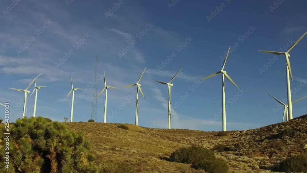 California Wind Turbines around Tehachapi in late winter with some snow on the ground.  Multiple wind turbines, large and small, some not working amid a forest of power lines and grids.