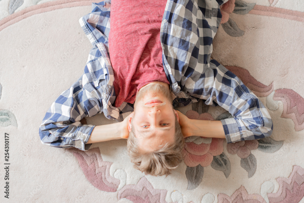 young man in shirt lay on the carpet and relax after busy day b