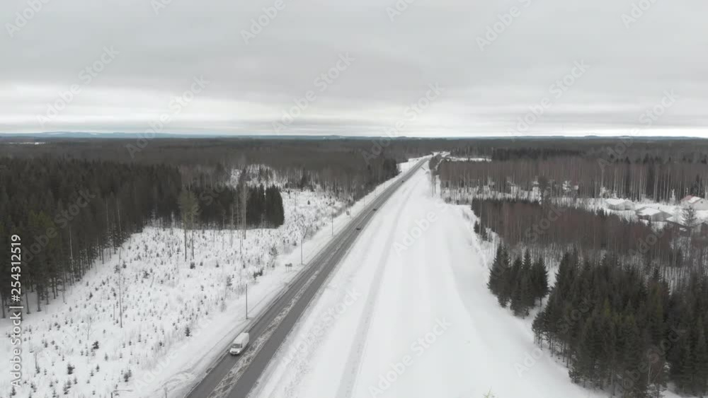 Aerial, tracking, drone shot, of traffic, on road 6, surrounded by snowless trees, on a cloudy, winter day, in Kontionlahti, North Karelia, Finland Aerial, tracking, drone shot, of traffic, on road 6, surrounded by snowless trees, on a cloudy, winter day, in Kontionlahti, North Karelia, Finland