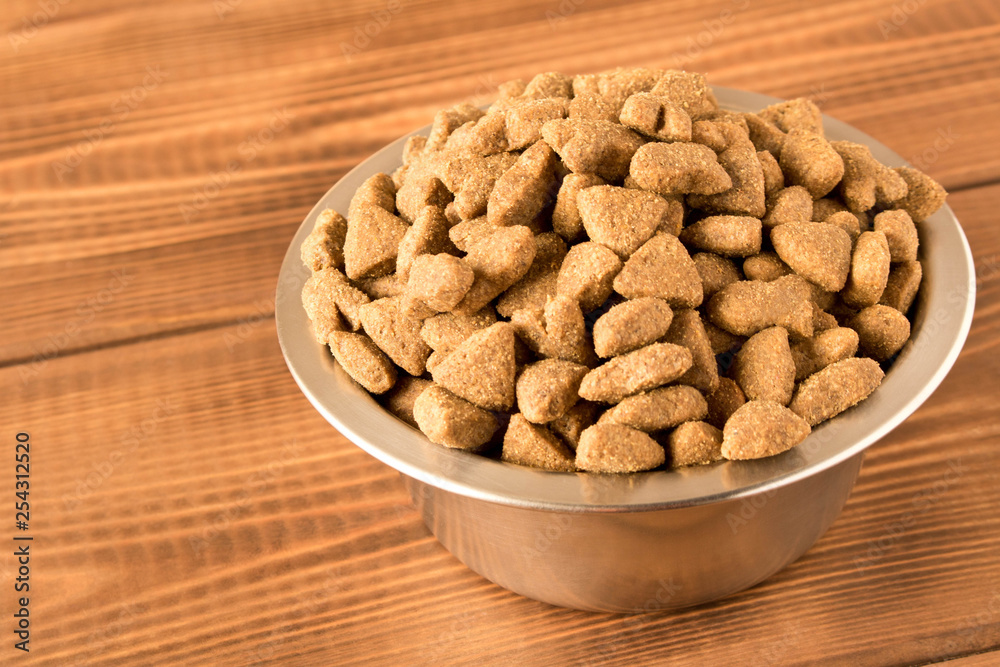 Bowl with dog food on a wooden table. Close up. Bowl with dog food on a wooden table. Close up.