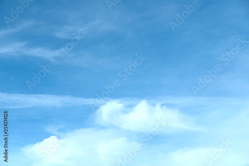 Blue sky background on a cloudy day. A group of white clouds at the bottom of the image. Cropped shot, horizontal, nobody. Concept of nature and beauty.