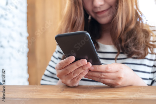 Closeup image of a beautiful asian woman holding , using and looking at smart phone in cafe