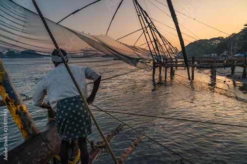 Foto man work at Chinese fishing nets during the Golden Hours at Fort Kochi, Kerala,