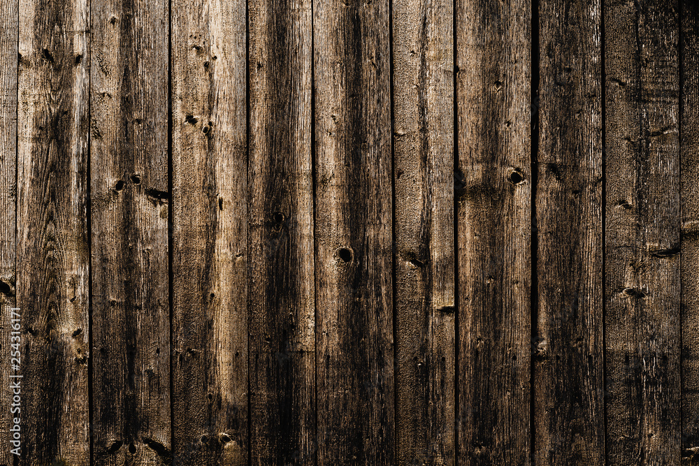 A wall made of old, dark, worn brown wooden knotty planks A wall made of old, dark, worn brown wooden knotty planks