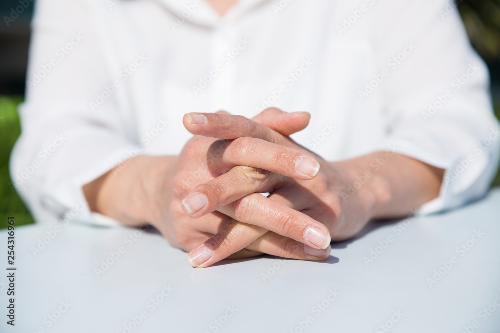 Closeup of woman relaxing at table with her hands clasped