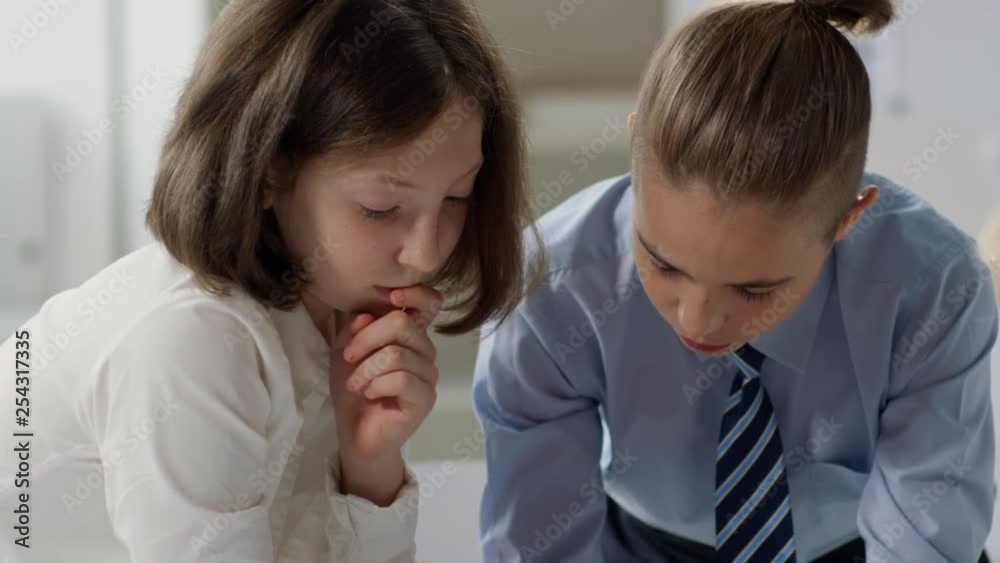 Several children in office clothes pretending to be businesspeople, sitting at desktop and working with papers Several children in office clothes pretending to be businesspeople, sitting at desktop and working with papers