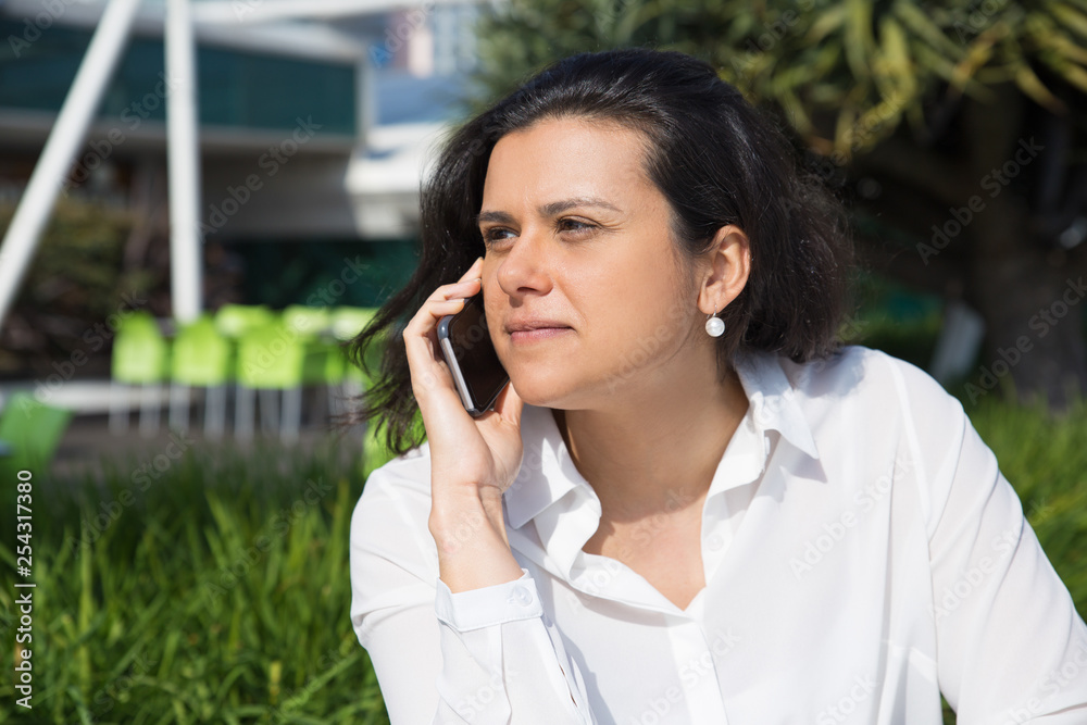 Serious attractive woman talking on mobile phone outdoors Serious attractive woman talking on mobile phone outdoors