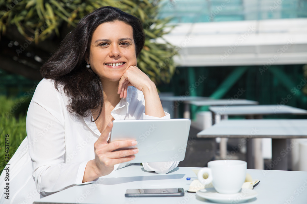 Smiling pretty woman working and using tablet in street cafe Smiling pretty woman working and using tablet in street cafe