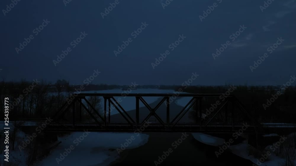 Small train bridge passing over a frozen river at winter sunrise Small train bridge passing over a frozen river at winter sunrise