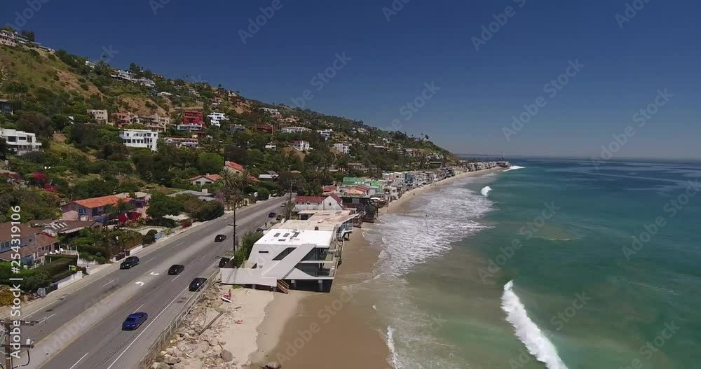 Cars drive down Pacific Coast Highway, California, beach houses and crashing ocean waves Cars drive down Pacific Coast Highway, California, beach houses and crashing ocean waves