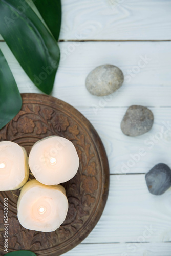 White candles, green leaves and grey stones. Concept of harmony, balance and meditation, spa, massage, relax.