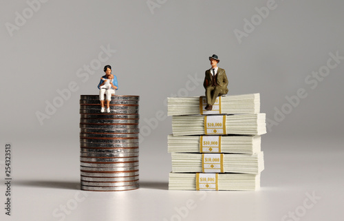 A pile of bills and coins. Miniature people. The concept of wage inequalities according to women's career break.
