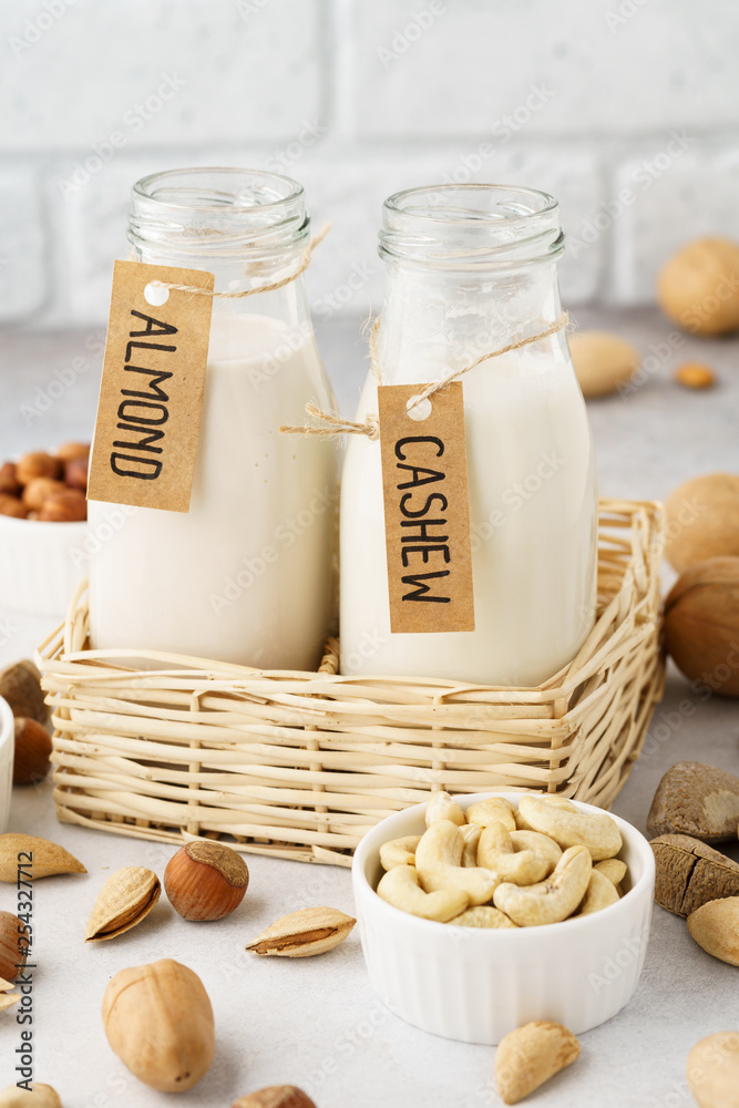 Vegan milk made of nuts in glass bottles - almond and cashew. Vegan milk made of nuts in glass bottles - almond and cashew.