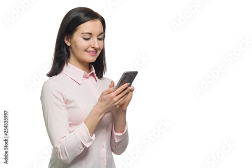 Young businesswoman in pink shirt using mobile phone on white isolated background. Woman writing or reading text message on modern smartphone, copy space