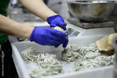 Male placed pasta nests on tray in kitchen